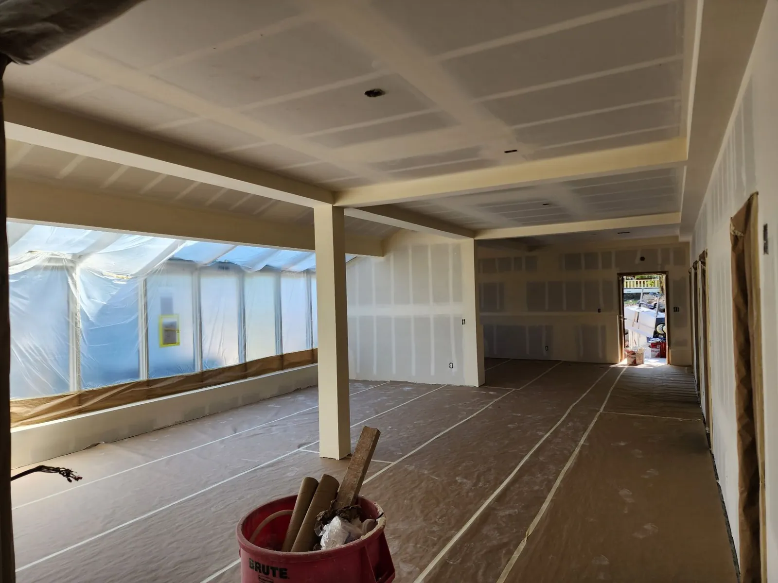 Drywall hanging in progress with the floor covered and the work area kept organized