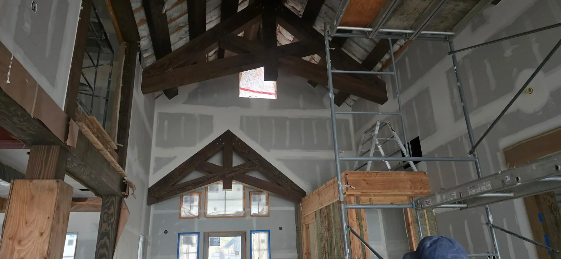 Large interior with drywall hung around wood trusses and a high ceiling